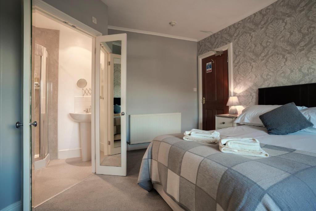 a bedroom with a bed and a bathroom with a sink at Lyndale Guest House in Ambleside