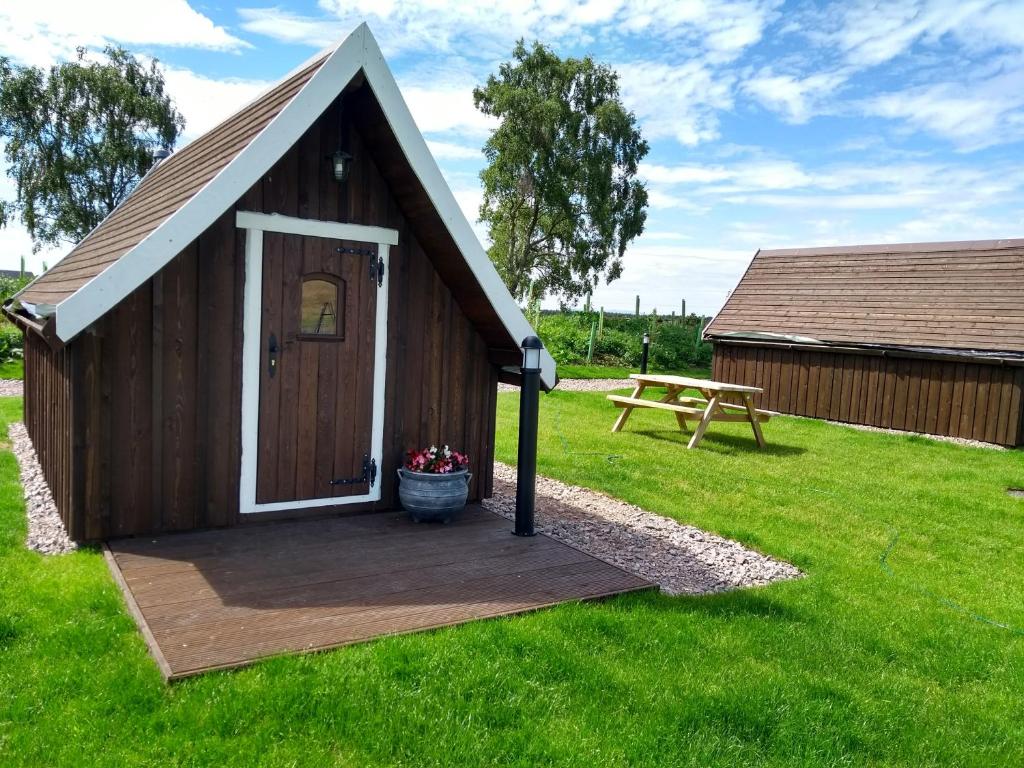 un pequeño cobertizo con porche y mesa de picnic en Macbeth's Hillock en Forres