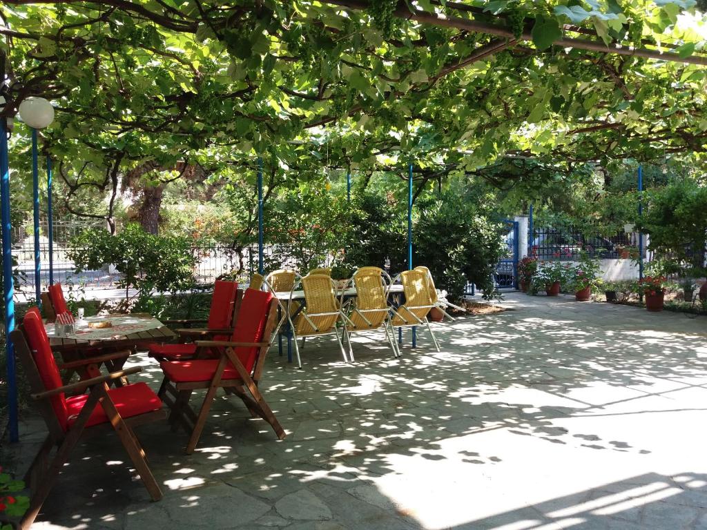 a patio with tables and chairs under a tree at Tasos Rooms in Prinos