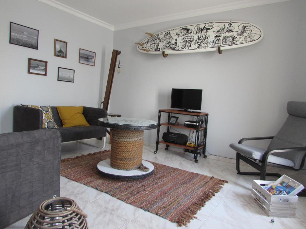 a living room with a table and a surfboard on the wall at Zambeachouse - Beach & Country in Lourinhã