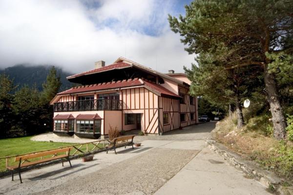 un grand bâtiment avec deux bancs devant lui dans l'établissement Hotel Temenuga, à Panichishte