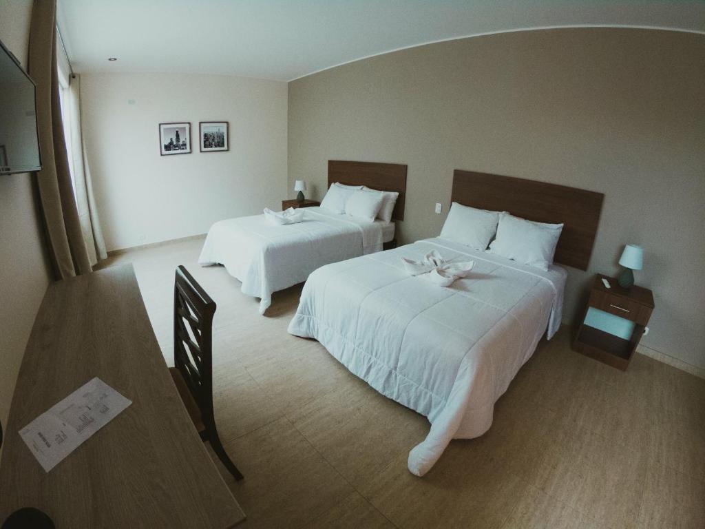 a hotel room with two beds with white sheets at Villa Oasis in Ica