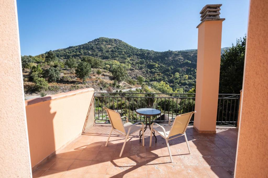 a balcony with a table and chairs and a mountain at Apartamentos Rurales El Solitario in Baños de Montemayor