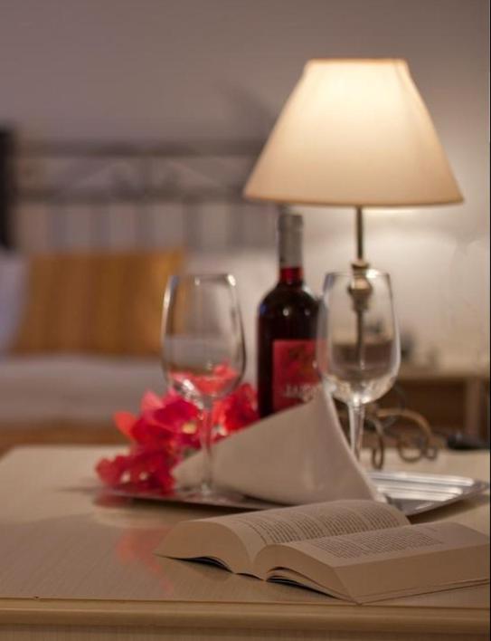 a table with a lamp and a book and wine glasses at Hotel Sylesia in Letojanni