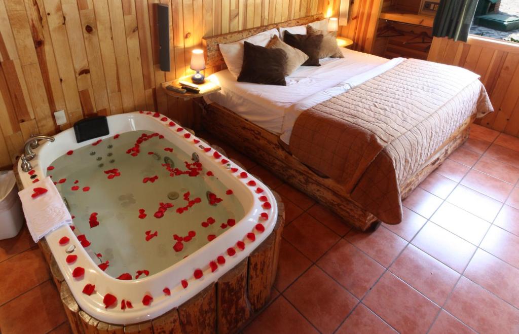 Un dormitorio con una cama y una bañera con rosas. en Cabañas El Estribo Hotel en Valle de Bravo