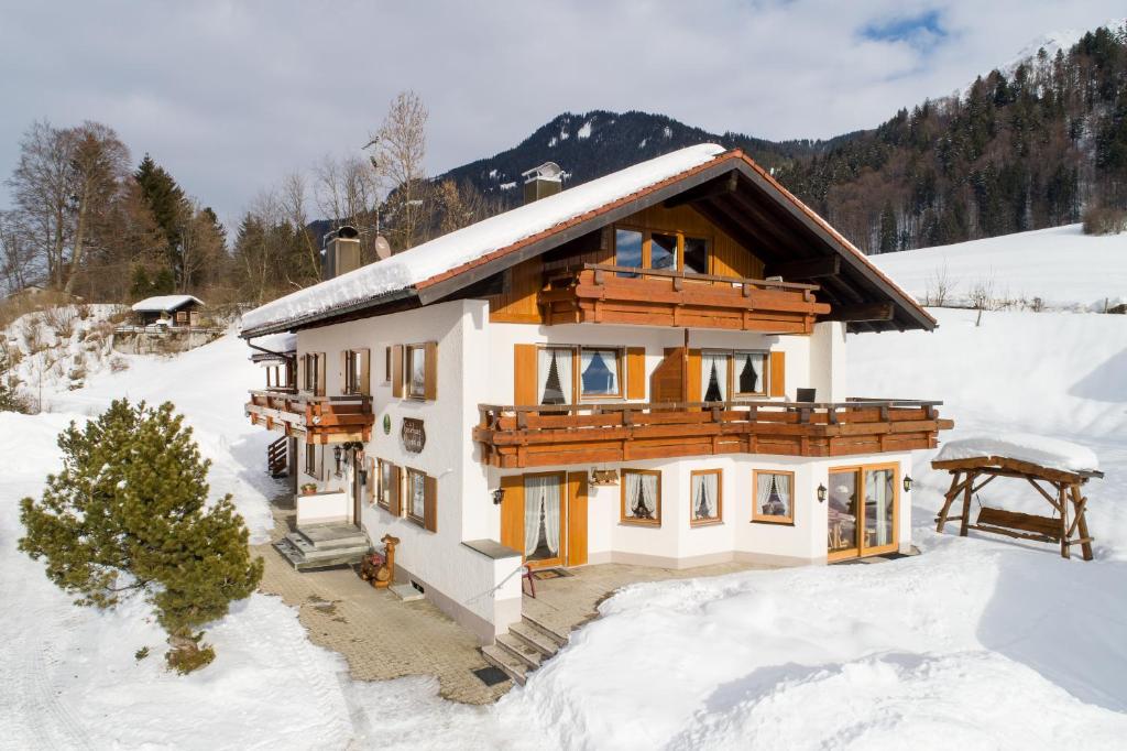 a house in the snow with snow at "Haus Alpenblick" - Annehmlichkeiten von 4-Sterne Familien-und Wellnesshotel Viktoria können mitbenutzt werden in Oberstdorf