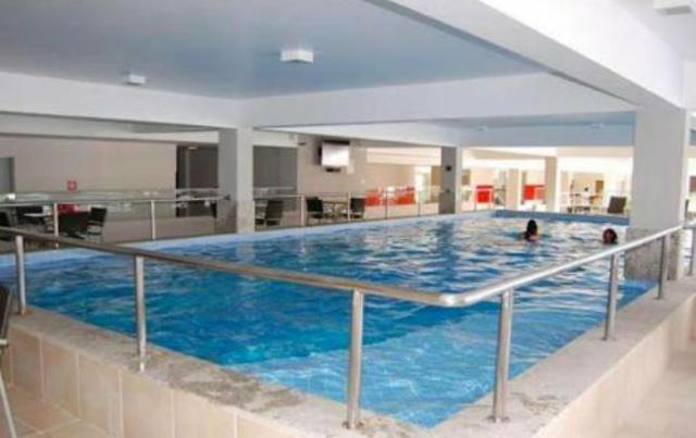 a large swimming pool with two people in it at Apartamento Veredas in Rio Quente