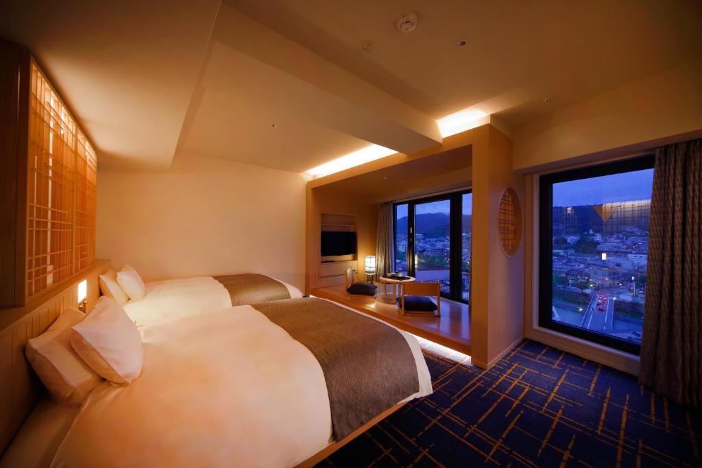 a hotel room with two beds and a large window at SH by the square hotel Kyoto Kiyamachi in Kyoto