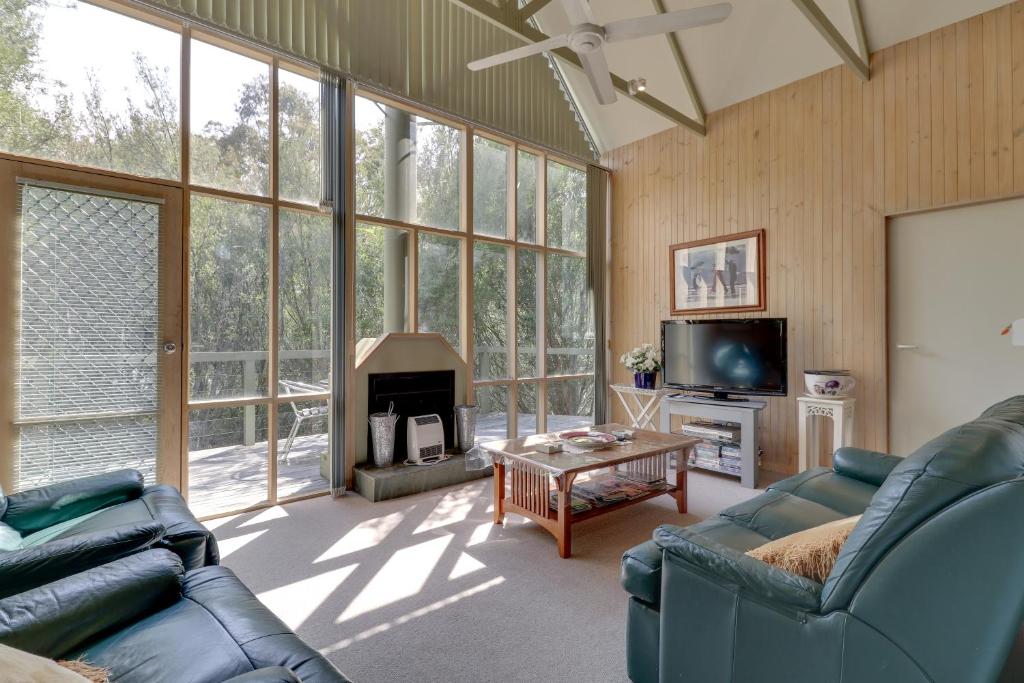 Una sala de estar con un sofá y una chimenea. en Casuarina, en Metung