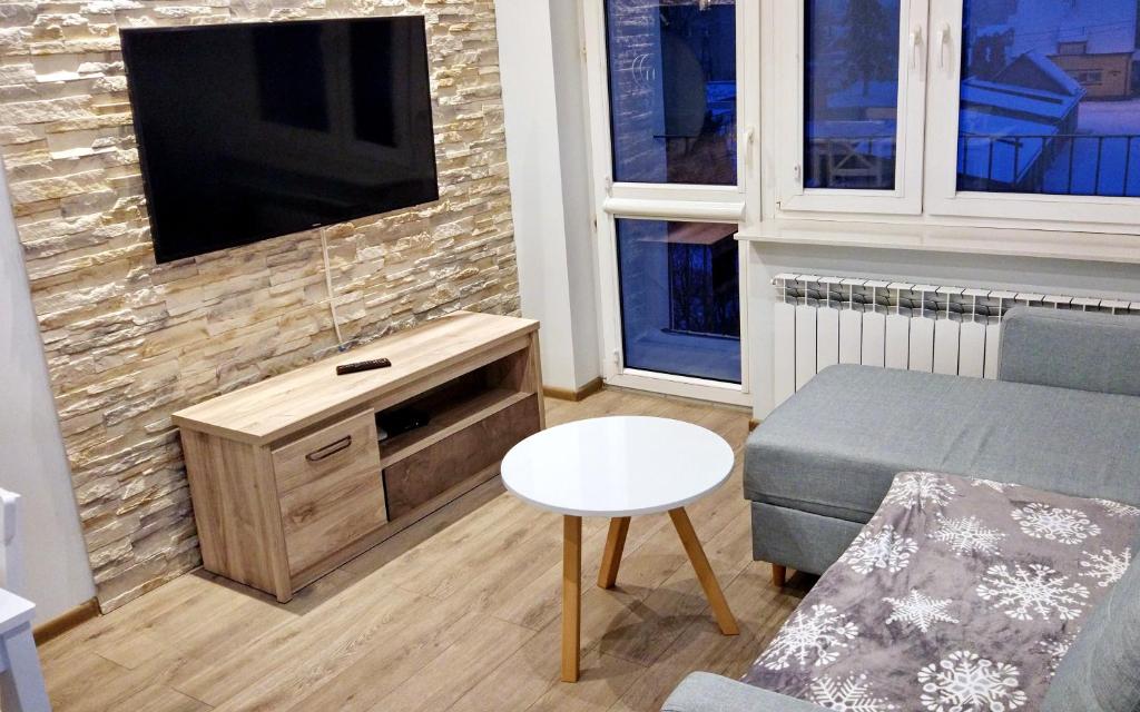 a living room with a couch and a tv on a brick wall at Przytulny Apartament w Gołdapi in Gołdap