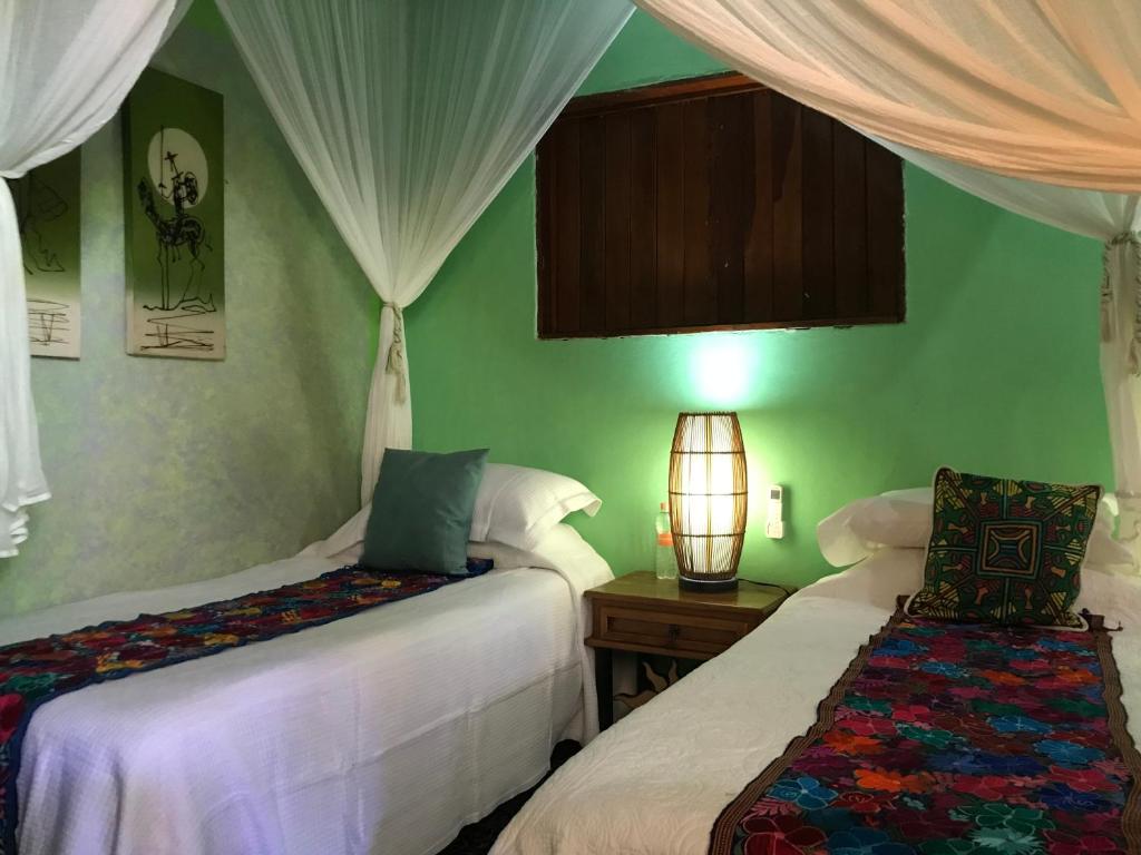 2 camas en una habitación con paredes y cortinas verdes en Casa Juanita, en Sayulita