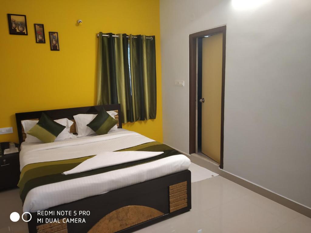 a bedroom with a bed with yellow walls and a mirror at NAMAHA STAYs in Shamshabad