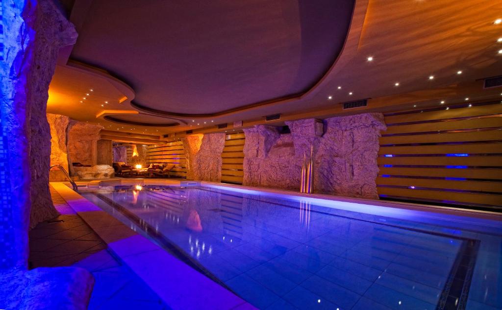a swimming pool in a house with purple lighting at Hotel Regina in San Martino di Castrozza