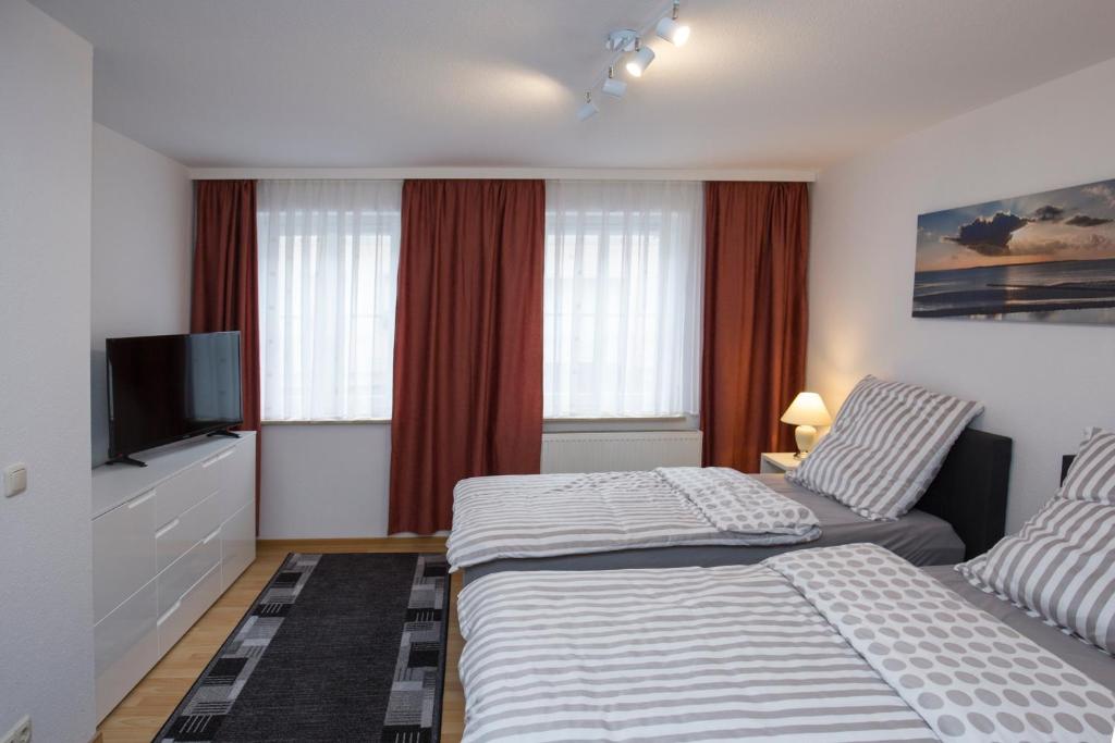 a hotel room with two beds and a flat screen tv at Ferienwohnungen Grimma 4 in Grimma