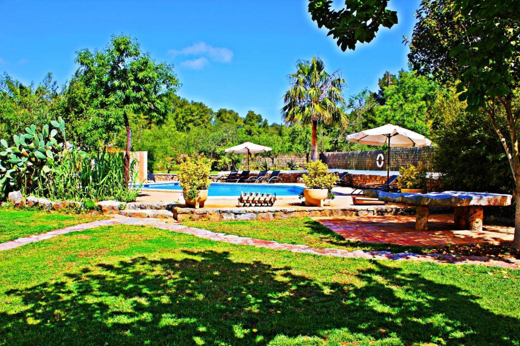 un patio con piscina, mesa de picnic y sombrillas en Agroturismo Can Fuster, en Sant Joan de Labritja