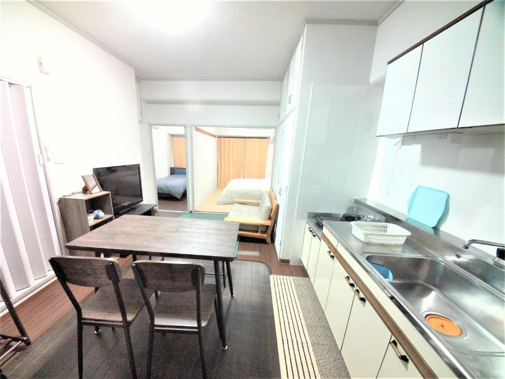 eine Küche und ein Esszimmer mit einem Tisch und Stühlen in der Unterkunft Near Tram Apartment Okayama in Okayama