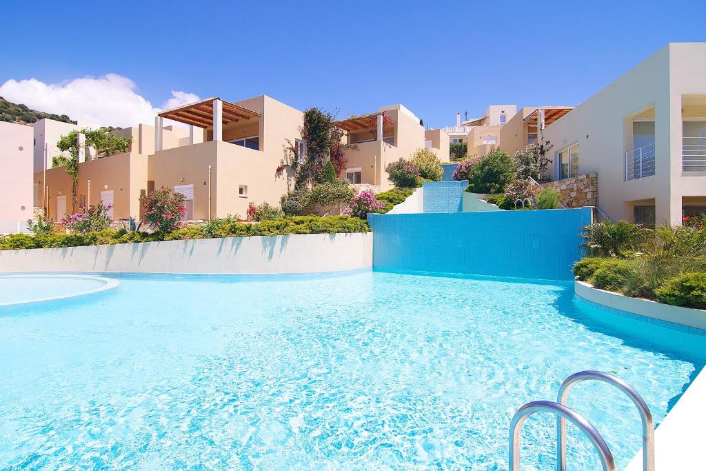 a swimming pool with blue water in front of some buildings at Plakias Panorama Homes in Plakias