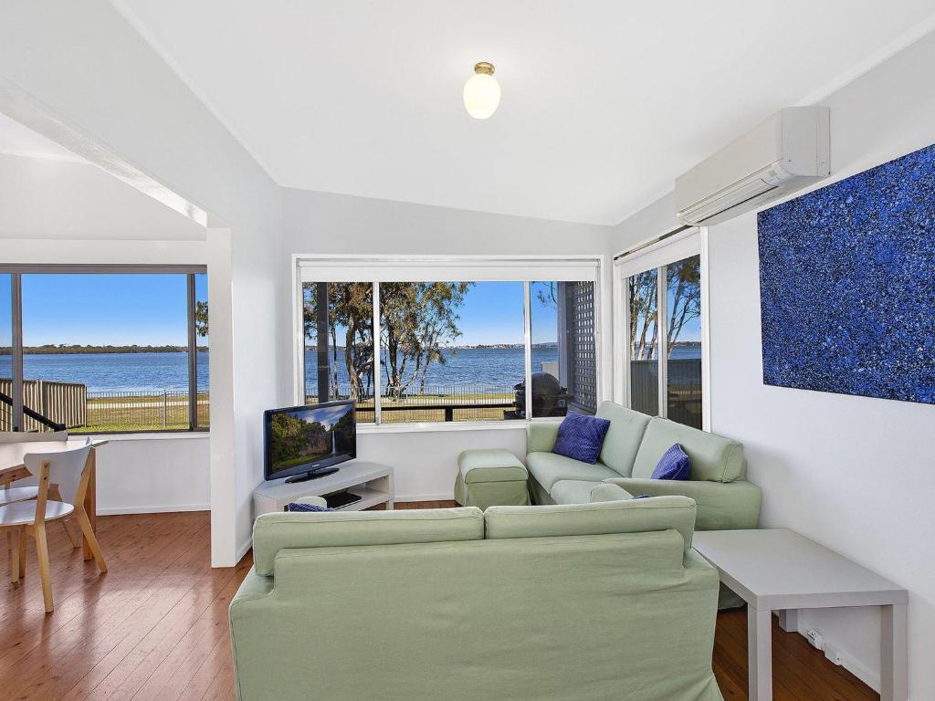 a living room with a couch and a tv at Lake Edge Cottage in Budgewoi