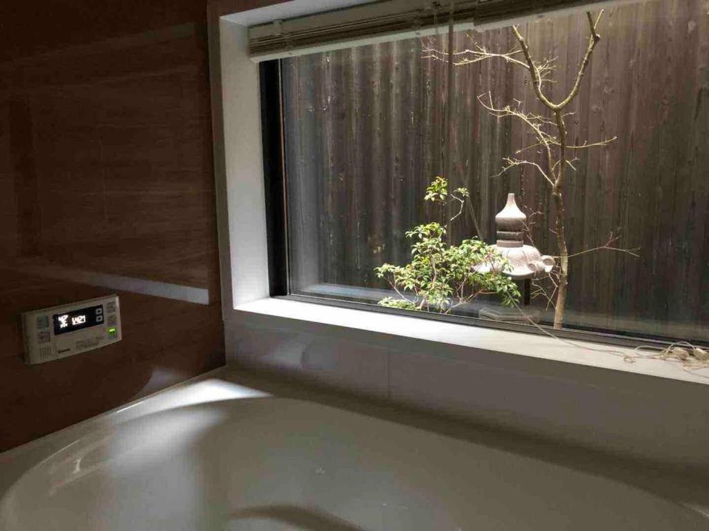 a bath tub in front of a window with a plant at FUUTEI Japanese-style lodge in Kyoto