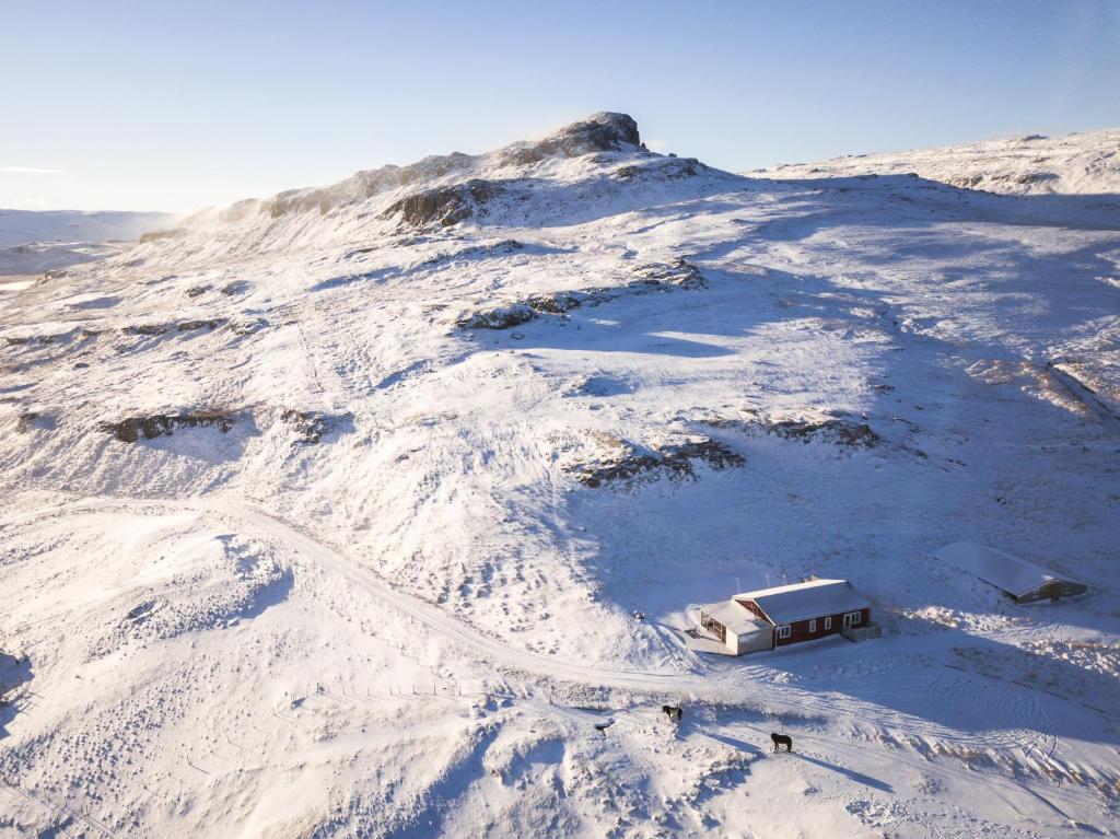 uma montanha coberta de neve com uma pequena casa em Litlabjarg Guesthouse em Hrafnabjorg