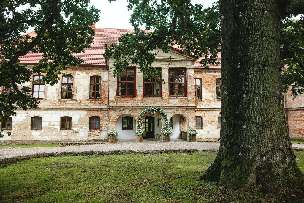 ein altes Steinhaus mit einem Baum davor in der Unterkunft Pałac Wielka Wieś - "Pałac pod Dębem" in Główczyce