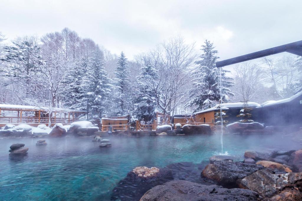 a hot tub with a fountain in the snow at Midorinokaze Resort Kitayuzawa in Date