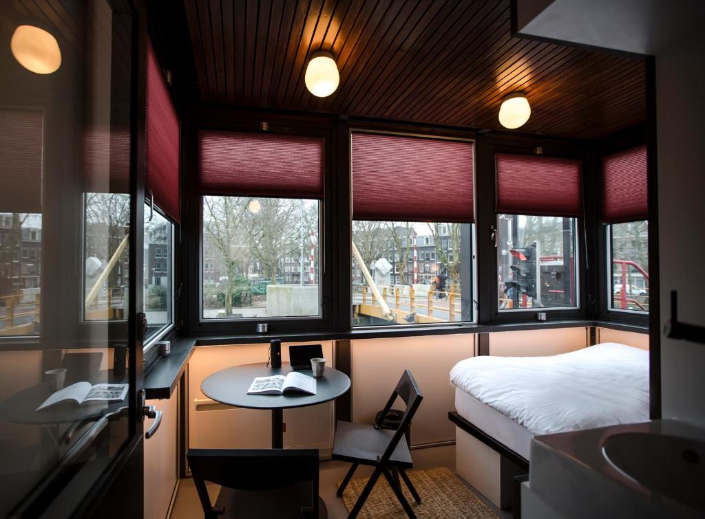 een kamer met een bed, een bureau en ramen bij SWEETS - Theophile de Bockbrug in Amsterdam