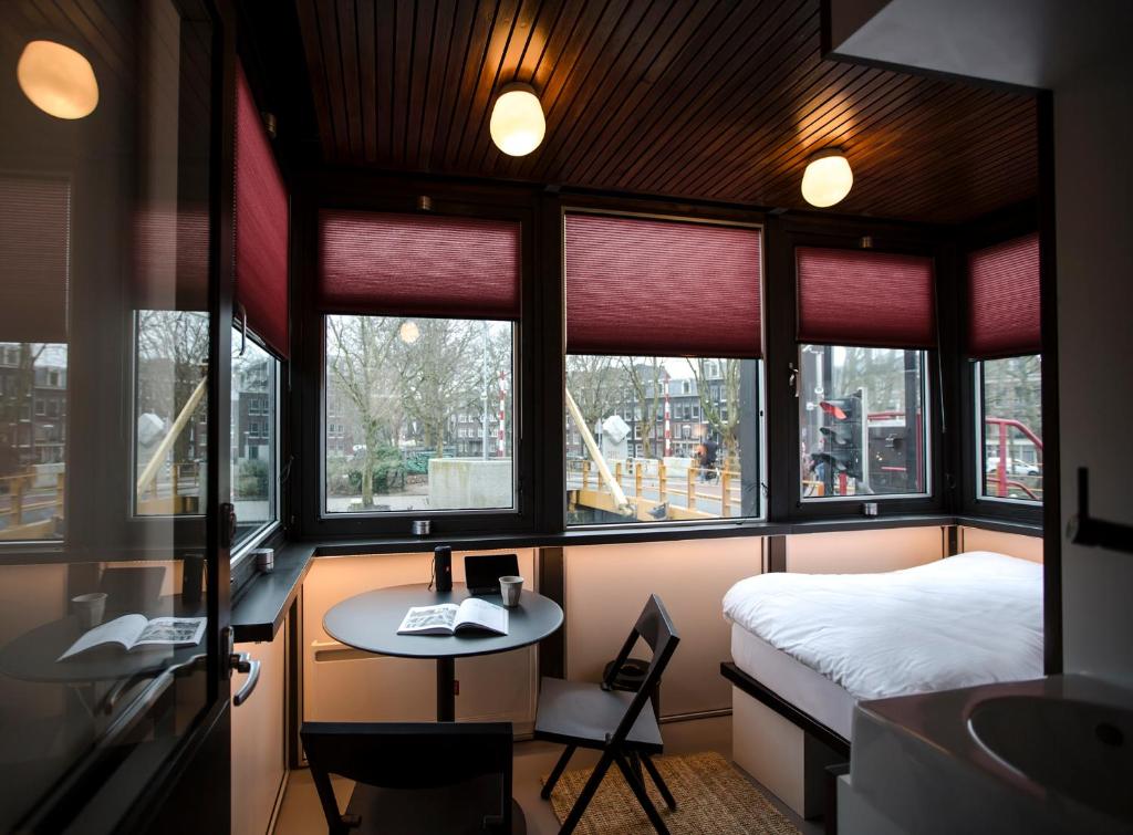 a room with a bed and a desk and windows at SWEETS - Theophile de Bockbrug in Amsterdam