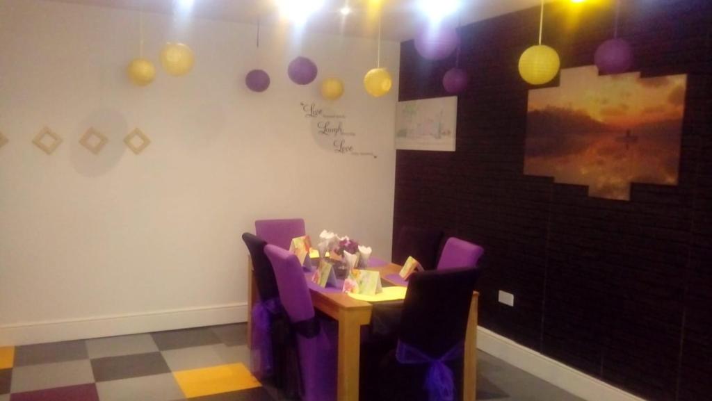 a room with a table with purple chairs and balloons at Carer 4 You Residential Home in Upholland