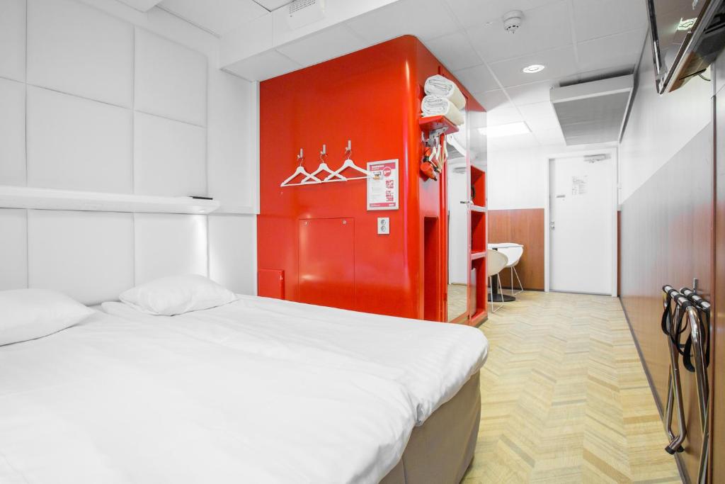 Cette chambre comprend un lit et un mur rouge. dans l'établissement Omena Hotel Helsinki Lönnrotinkatu, à Helsinki