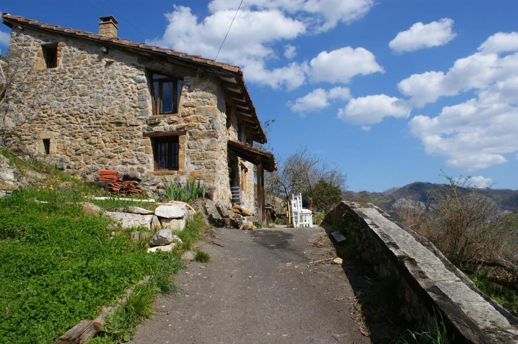 une vieille maison en pierre sur une colline avec un pont dans l'établissement La Cabaña del Beyu Pen, à Amieva