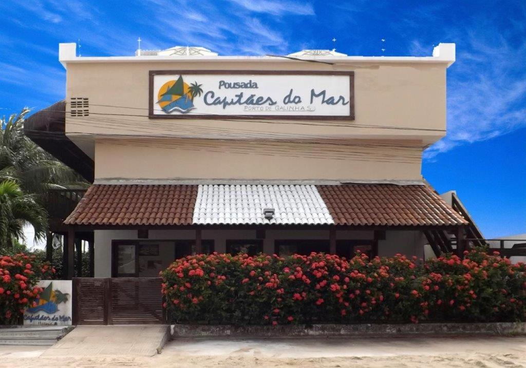 a building with a sign for a restaurant with flowers at Pousada Capitães do Mar in Porto De Galinhas