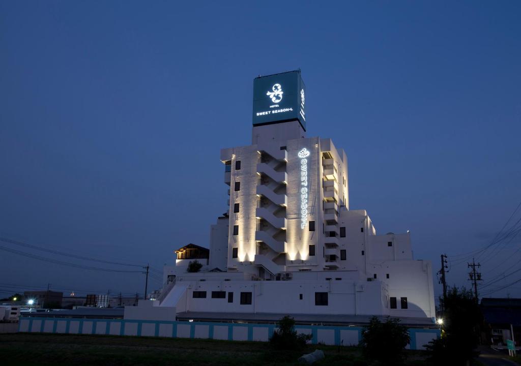 HOTEL SWEET SEASON-L في Ginan: مبنى أبيض كبير مع علامة في الأعلى في الليل