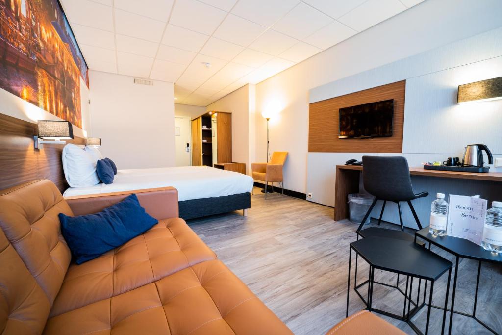 een hotelkamer met een bank en een bed bij Tulip Inn Leiden Centre in Leiden