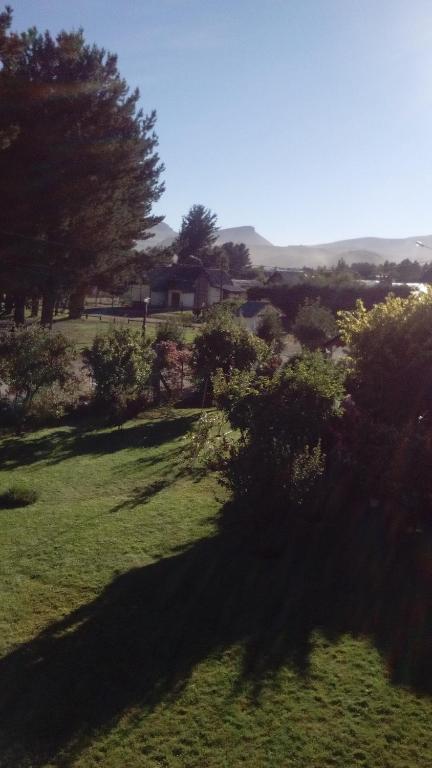 a field of grass with trees and a house in the background at Montalto in Dina Huapi
