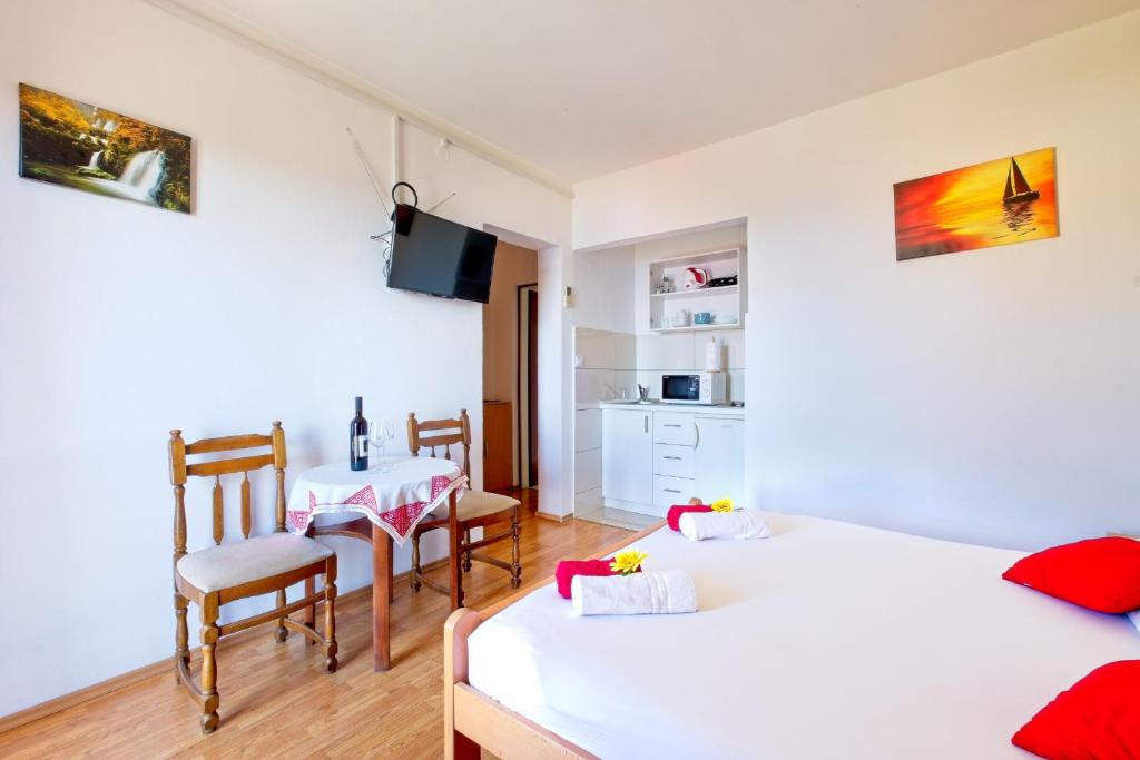 1 dormitorio con 2 camas, mesa y sillas en Guest House Račić, en Mlini