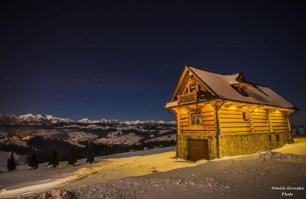 a wooden cabin in the snow at night at Dom Pod Bachledówką in Czerwienne