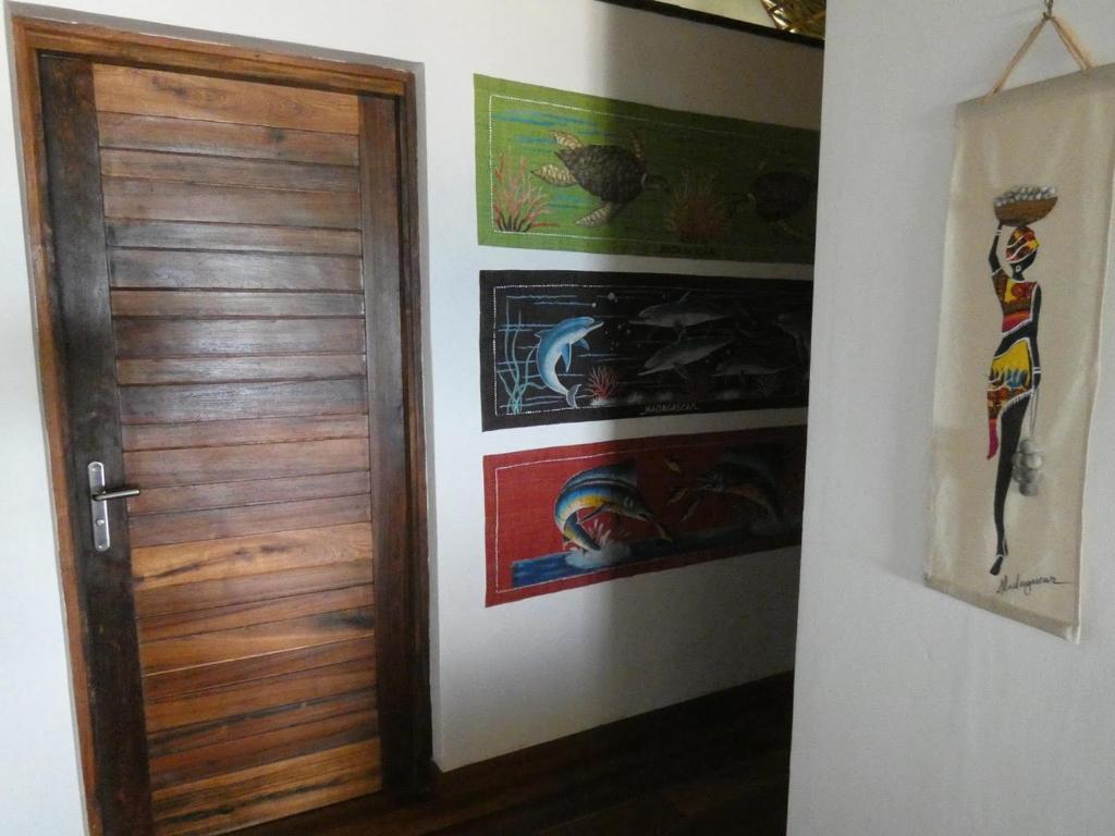 a door in a room with paintings on the wall at LE TRANSAT in Ambatoloaka