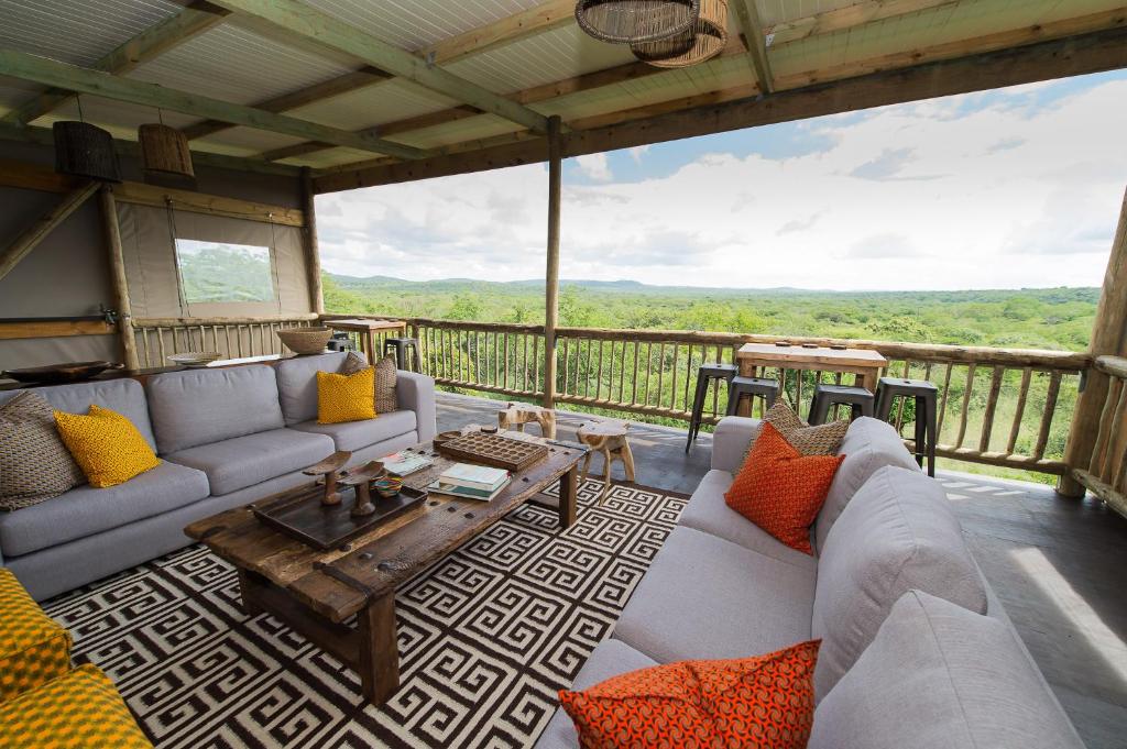 una sala de estar con sofás y una mesa en el balcón en Zululand Lodge, en Hluhluwe