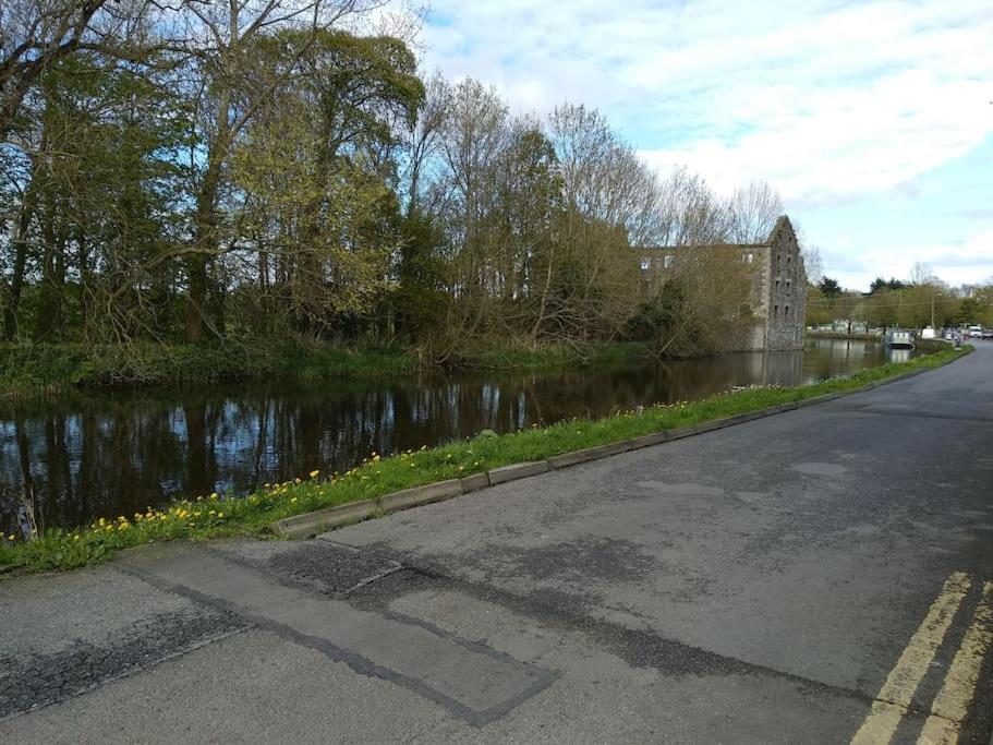 eine leere Straße neben einem Fluss mit einem Gebäude in der Unterkunft Small Town House, Barrow Lane, Bagenalstown, Carlow in Bagenalstown