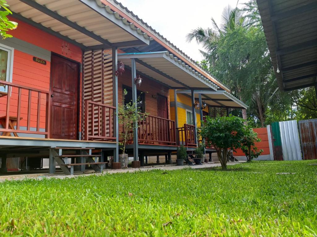 una casa con porche y patio de césped en Aroonsri Thara, en Ratchaburi