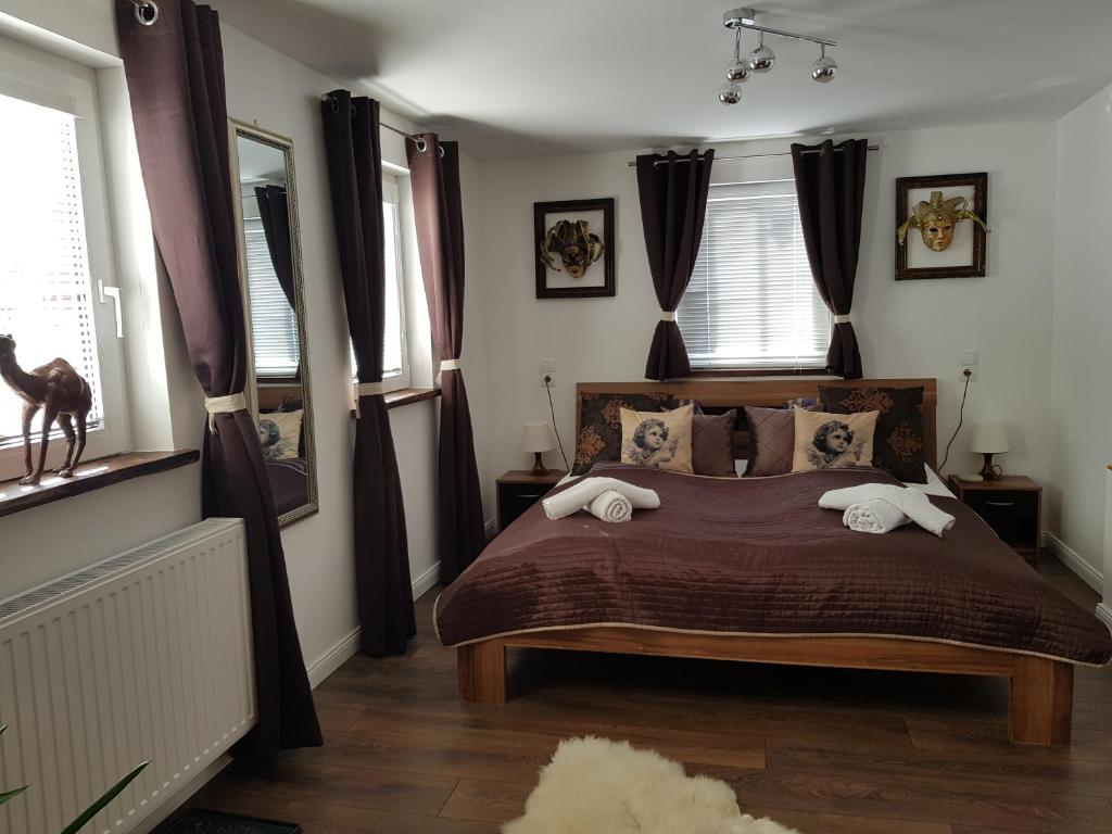 Schlafzimmer mit einem Bett mit Kissen und Vorhängen in der Unterkunft Alexandra Appartement in Gersdorf