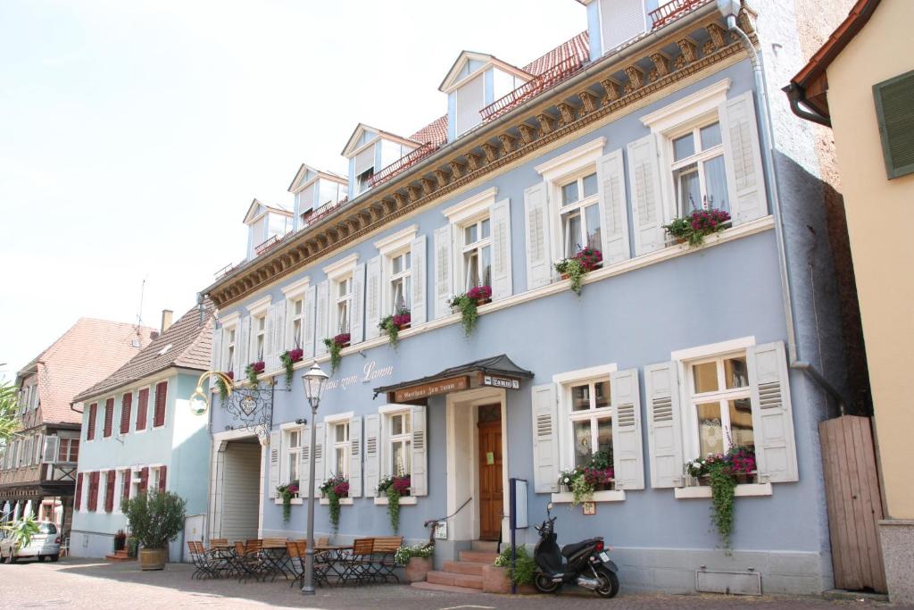 a blue building with white windows and a scooter parked in front at Gasthaus zum Lamm in Ettenheim