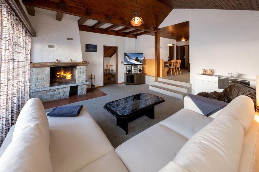 sala de estar con sofá y chimenea en Fortuna Dachgeschoss, en Grächen