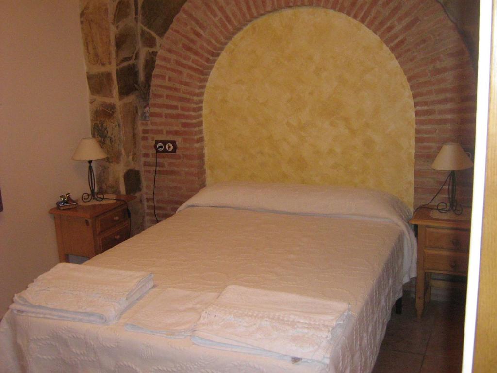 1 dormitorio con 1 cama con pared de ladrillo en Hostal Sara, en Villafeliche