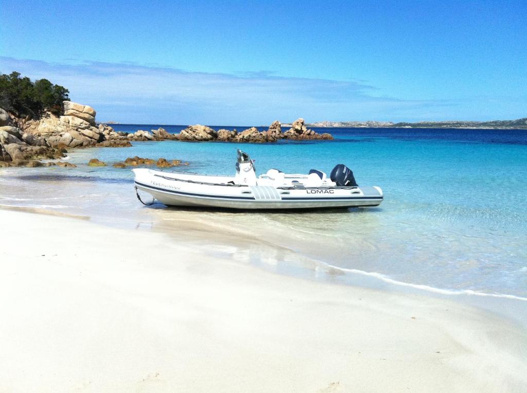 Una lancha rápida sentada en la orilla de una playa en Hotel Villa Del Parco, en La Maddalena