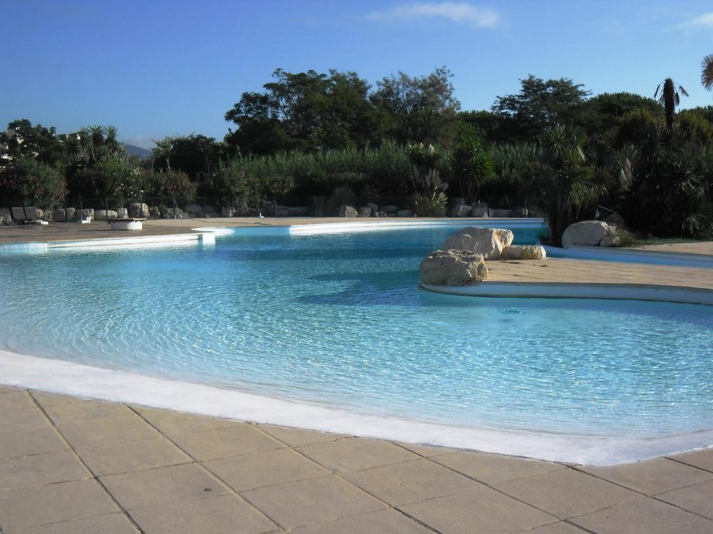 a swimming pool with blue water and rocks at GASYAN - Golfe de St-Tropez - Appartement aves accès plage dans résidence avec piscine in Gassin