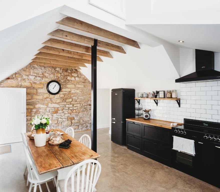 a kitchen with a wooden table and white chairs at Orchard Cottage in St. Andrews