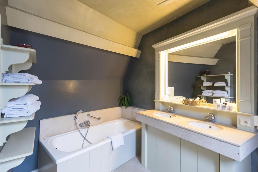 a bathroom with a sink, mirror, and bathtub at Hotel Ter Brughe in Bruges