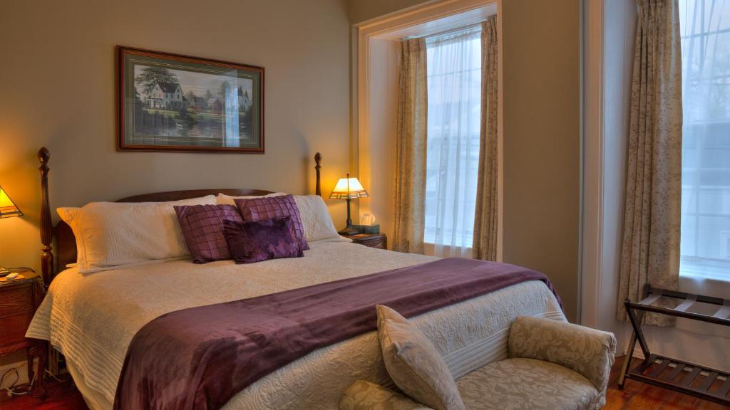 a bedroom with a large bed and a chair at Sir Isaac Brock B&B Luxury Suites in Brockville